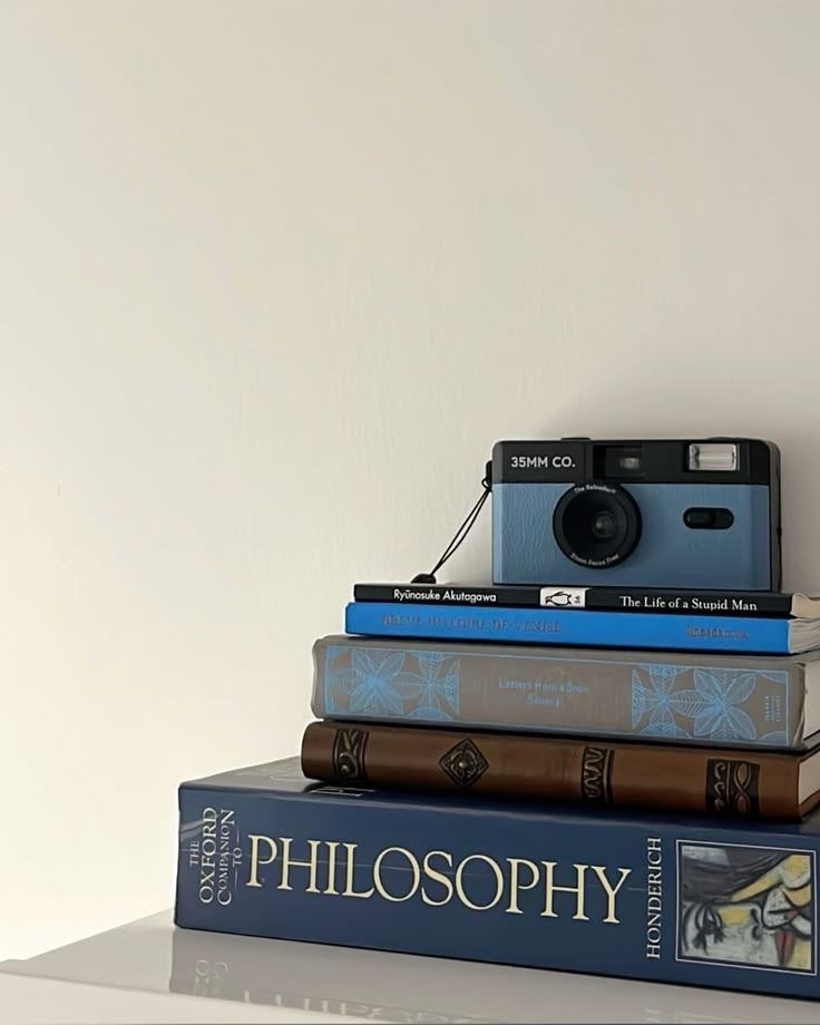 A stack of philosophy books with a film camera on top